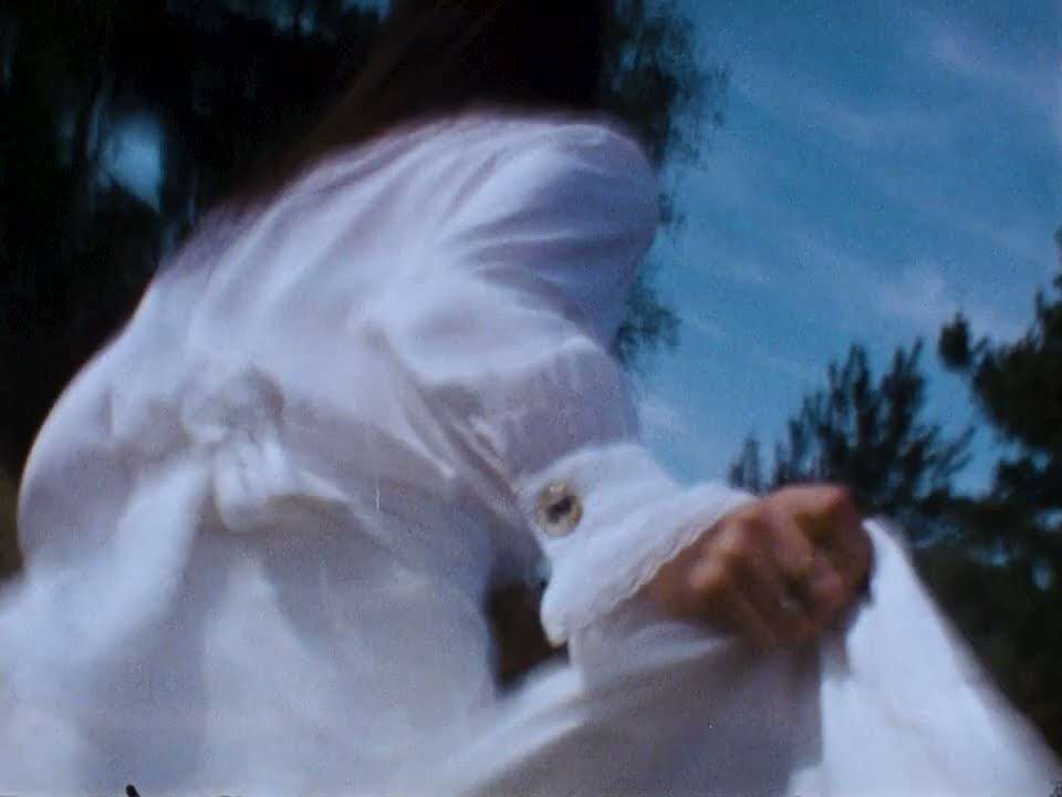 A white dress caught in the wind against a blue sky. Still from the ochtend video.